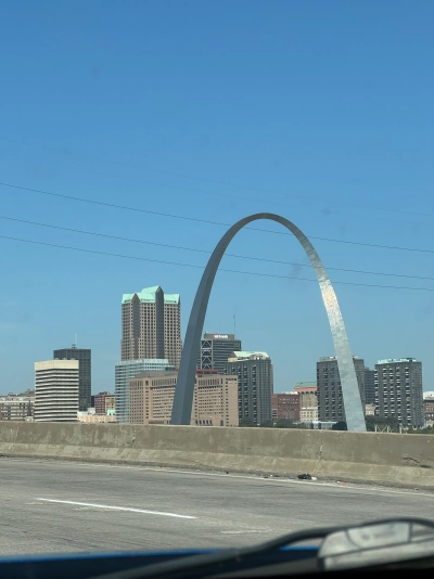 View of the St. Louis Arch from the driver's seat on Interstate 70 westbound. A US Bank skyscraper is visible underneath the arch.