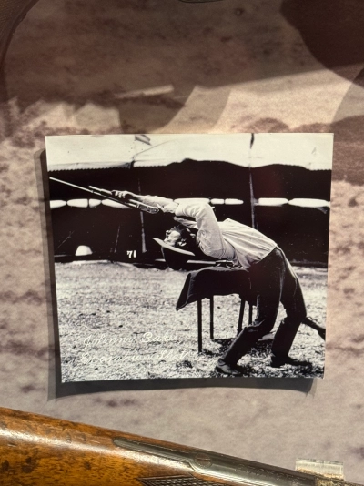 Photograph in the Buffalo Bill Museum of a man shooting a rifle behind him by leaning back at a 90 degree angle and craning his neck, basically forming an upside-down J shape with his body.