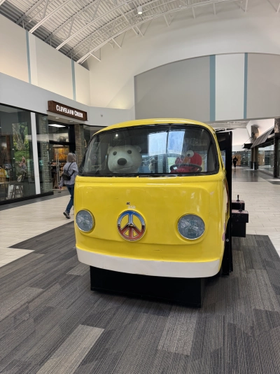 A toy Volkswagen bus in the Colorado Mills mall with a peace sign on the front. Elmo is driving and a polar bear is in the passenger seat.