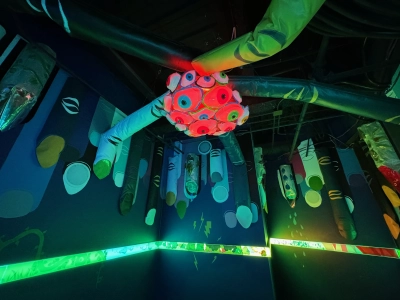 A multicolored exhibit inside the Meow Wolf in downtown Denver. A globe covered in human eyeballs is in the center of the ceiling, with inflatable pillars branching out and connecting to the walls. Various natural elements (vines, lightning bolts, water droplets) are painted on the walls.