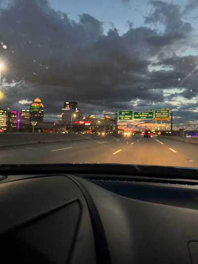 View from the driver's seat on Interstate 64 westbound , with a blurred Louisville skyline in the background. The bottom third of the photo is the dashboard of the Mazda.